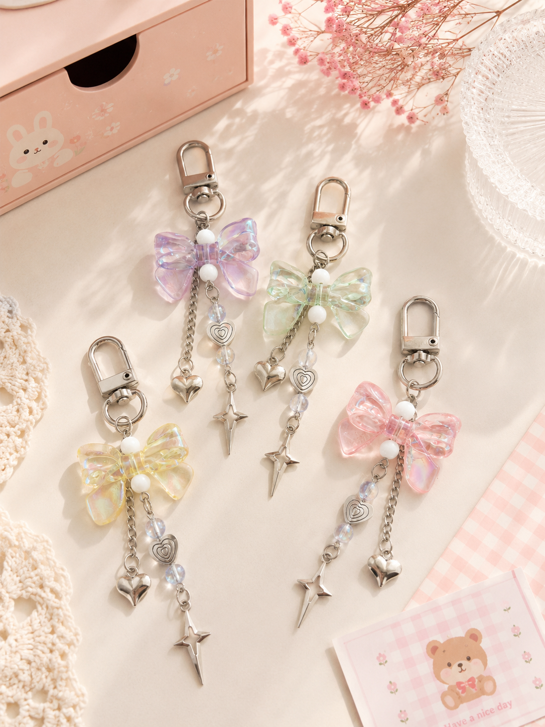 4 porte-clés nœud cristal iridescent avec chaîne cœur et étoile argentée en 4 coloris : violet, vert menthe, jaune pastel et rose